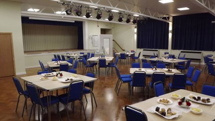 A hall set up with tables and chairs with plates of food